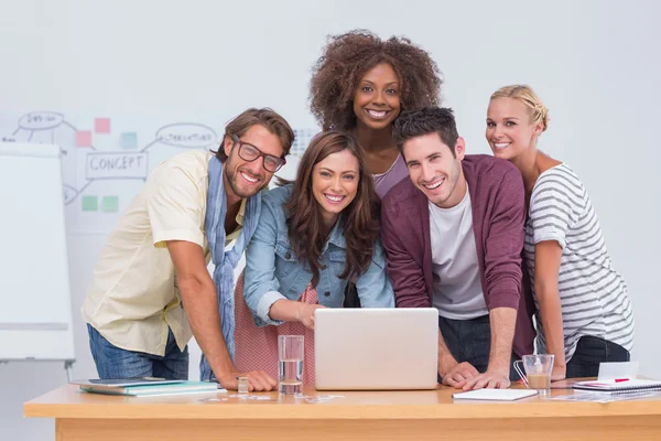 Equipo creativo de pie en el escritorio con ordenador portátil —  Fotos de Stock