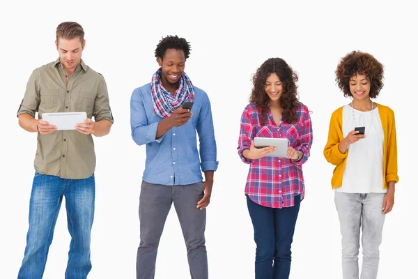 Fashionable friends standing in a row using media devices — Stock Photo, Image