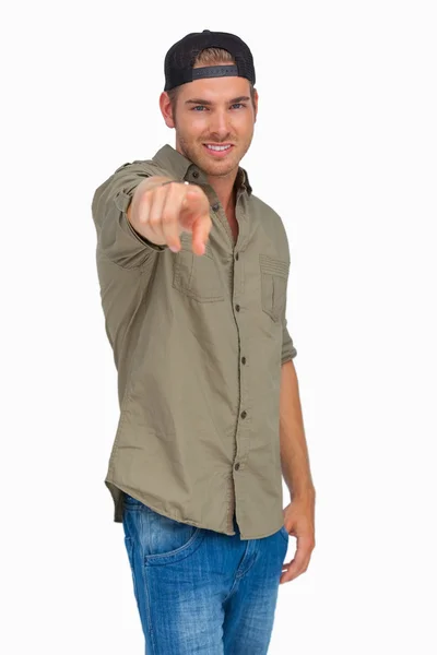 Man smiling and wearing baseball hat backwards and pointing — Stock Photo, Image