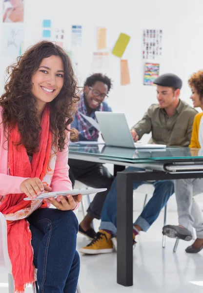 Lachende vrouw met behulp van Tablet PC met creatieve team werken achter — Stockfoto