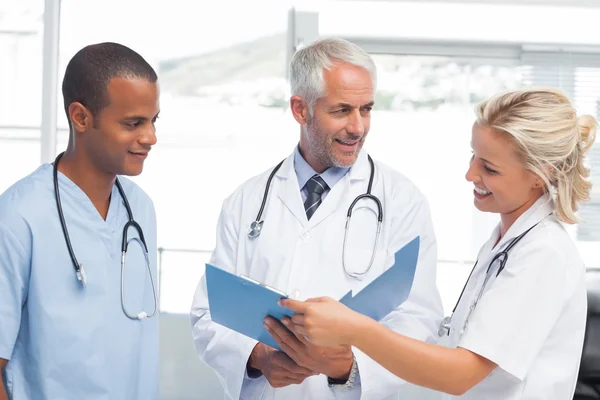 Tres doctores sonrientes examinando un archivo — Foto de Stock