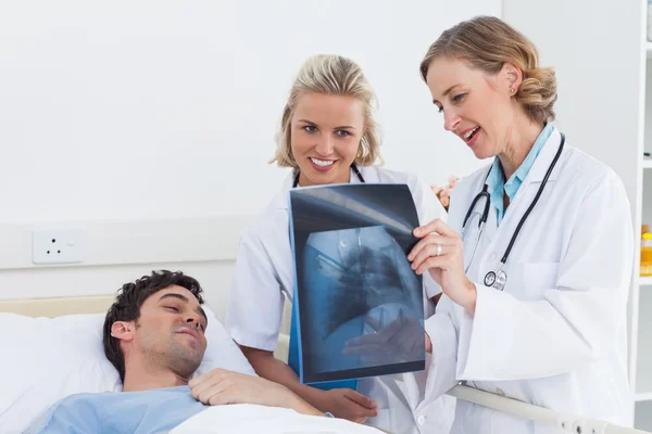 Dos mujeres doctores mostrando rayos X a un paciente — Foto de Stock