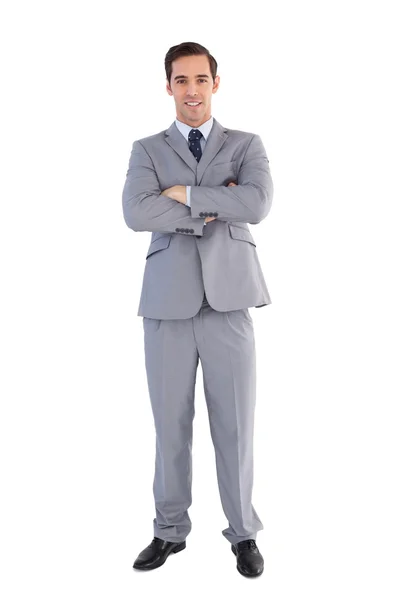 Улыбающийся бизнесмен стоит со скрещенными руками — стоковое фото