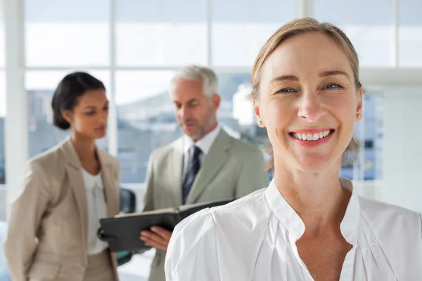 Glada affärskvinna står med kollegor som arbetar bakom — Stockfoto
