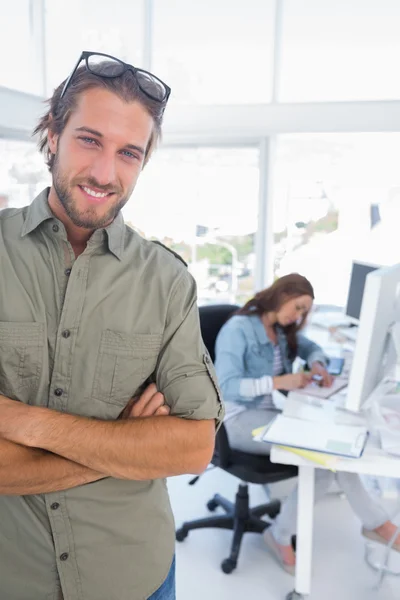 Man smiling in creative office with arms folded — Stock Photo, Image