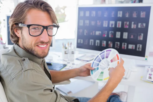 Photo editor looking at colour wheel and turning to smile — Stock Photo, Image