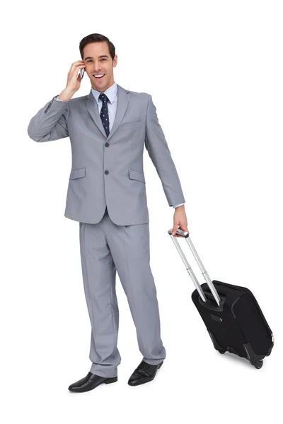 Happy young businessman with his luggage while phoning — Stock Photo, Image