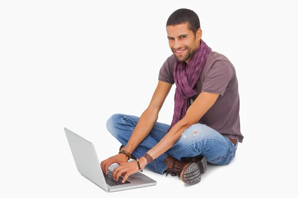Szczęśliwy człowiek siedzi na podłodze przy użyciu laptopa — Zdjęcie stockowe