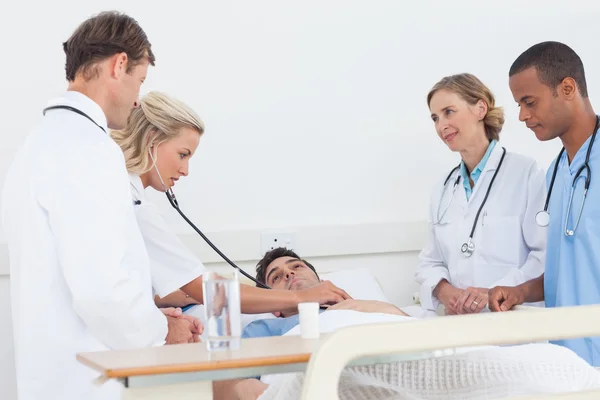 Equipe médica tomando o batimento cardíaco de um paciente — Fotografia de Stock