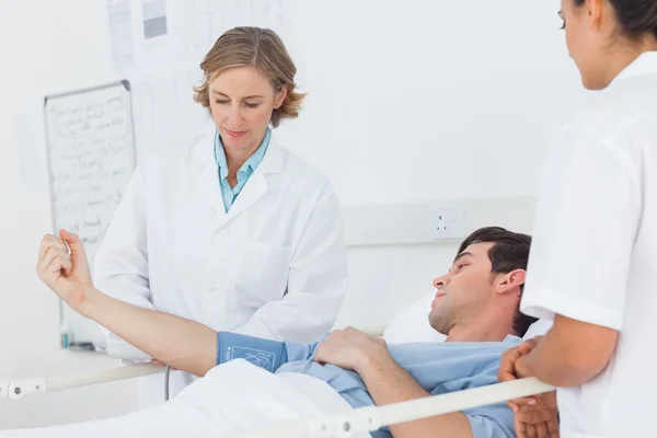 Doctors measuring the blood pressure of a male patient — Stockfoto