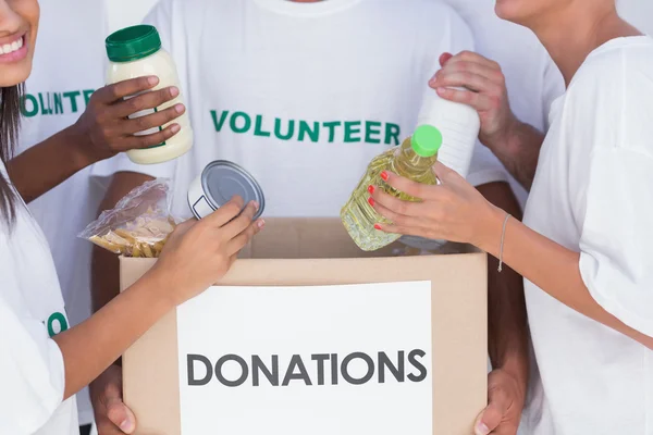 Voluntarios poniendo comida en la caja de donaciones — Foto de Stock