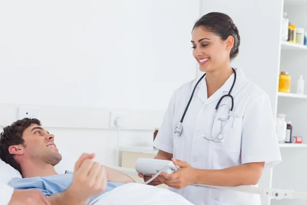 Attractive nurse measuring the blood pressure of a patient — Stock Photo, Image