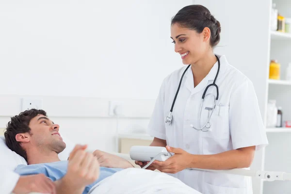 Attractive doctor taking the blood pressure of a patient — Stock Photo, Image