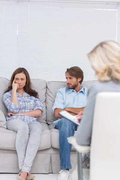 Troubled couple sit with arms folded — Stock Photo, Image