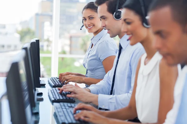 Smiling call centre employees working on computers — Stock Photo, Image