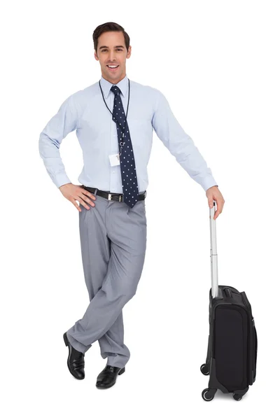 Улыбающийся бизнесмен рядом со своим чемоданом — стоковое фото