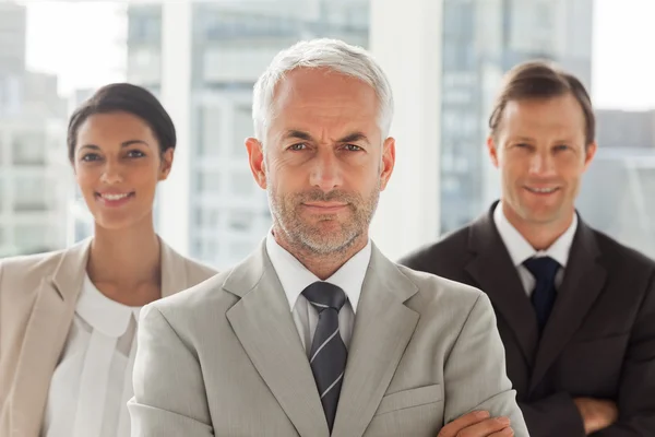 Businessman standing with colleagues behind — Stock Photo, Image