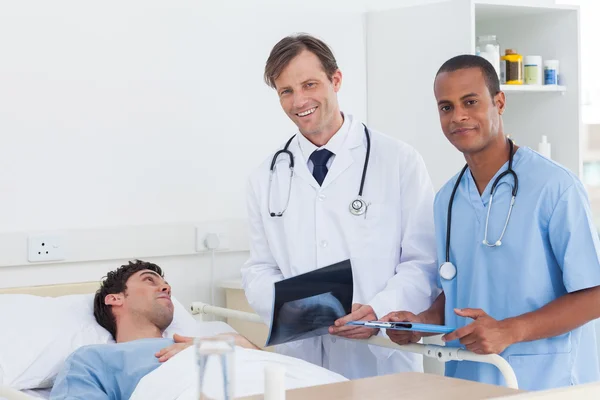 Médicos con radiografía de pie junto a un paciente — Foto de Stock