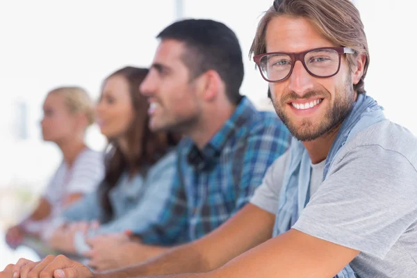 Kreativa team sitter i en linje med en man som ler — Stockfoto