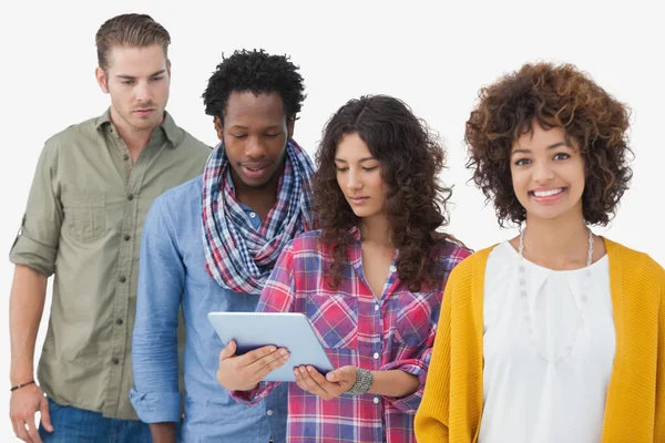 Four stylish friends in row with three looking at tablet — Stock Photo, Image