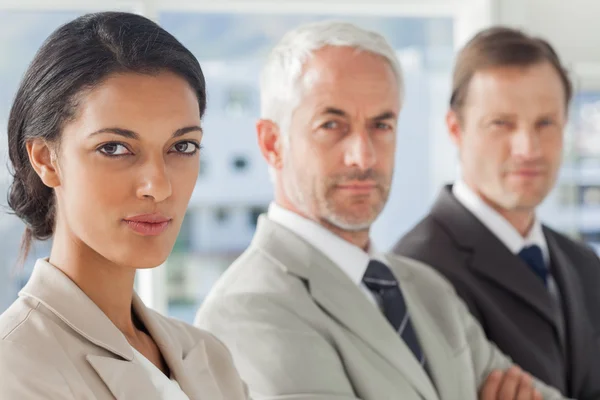 Mujer de negocios seria sonriendo con sus colegas detrás — Foto de Stock