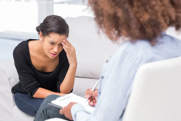 Woman crying on sofa while therapist is taking notes — Stock Photo, Image