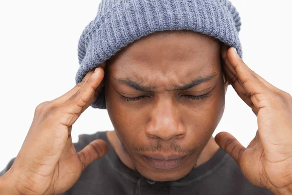 Человек в шапочке шапочке гримасит от головной боли. — стоковое фото
