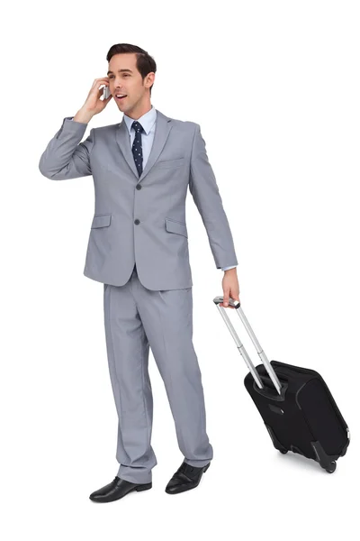 Jovem empresário sorridente com sua bagagem enquanto telefona — Fotografia de Stock