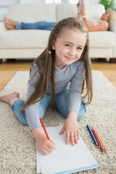 Happy girl drawing with her mother reading newspaper — Stock Photo, Image