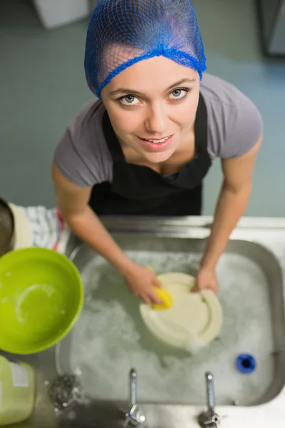 Donna sorridente alzando gli occhi dal lavarsi i piatti — Foto Stock