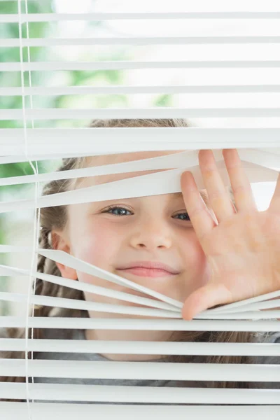 Happy child peeking through blinds — Stock Photo, Image