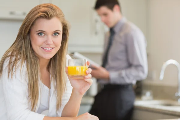 Νεαρή γυναίκα πίνοντας χυμό πορτοκαλιού στην κουζίνα — Φωτογραφία Αρχείου