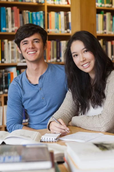 Två glada studenter i ett bibliotek — Stockfoto