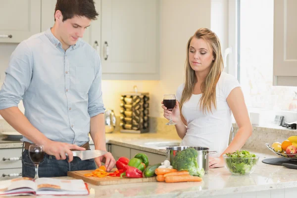 Uomo cucina con donna bere vino rosso — Foto Stock