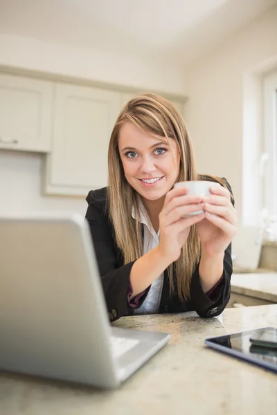 Kvinna dricka en dryck medan du arbetar på laptop — Stockfoto