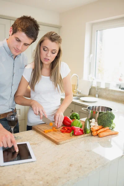 Casal olhando para tablet pc enquanto cozinha — Fotografia de Stock