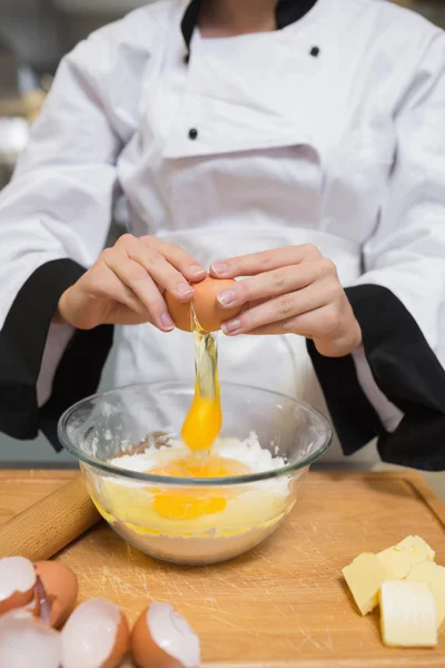 Chef breaking eggs into flour — Stock Photo, Image