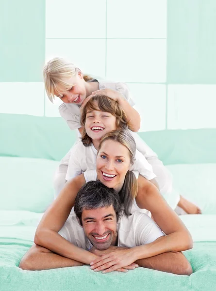 Smiling family piled on top of dad — Stock Photo, Image