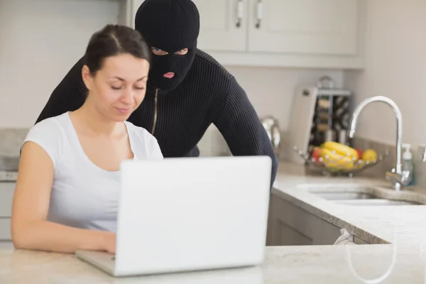Frau benutzt Laptop, während Einbrecher zusieht — Stockfoto