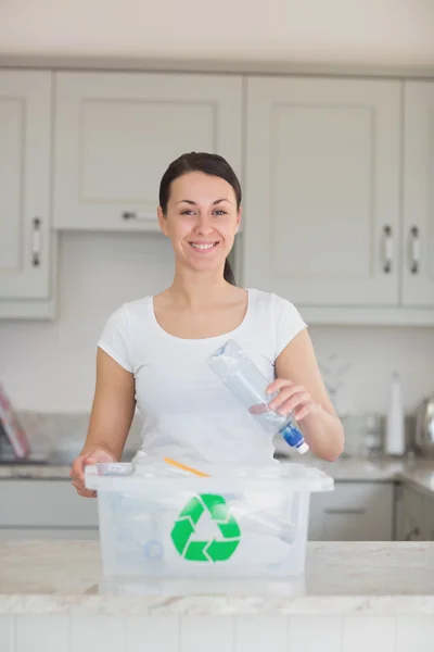 Smiling woman throwing bottle into recycling bin — Stock Photo, Image