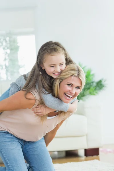 Madre dando hija un cerdito espalda — Foto de Stock