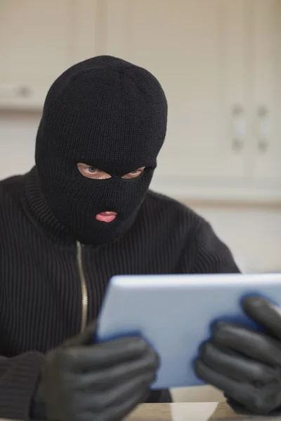 Burglar looking at tablet pc — Stock Photo, Image