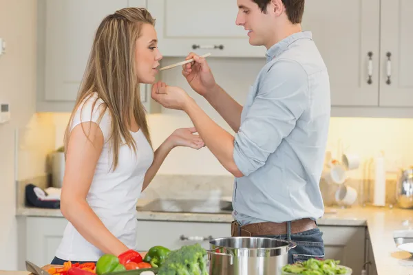 Woman tasting sauce from pot — Stock Photo, Image