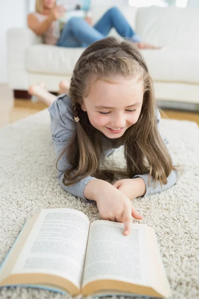 Flickan läsa bok med sin mamma som läser tidningen — Stockfoto