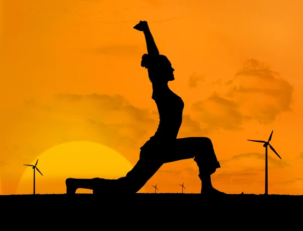 Rüzgar türbinleri ile yoga yaparken kadın silüeti — Stok fotoğraf