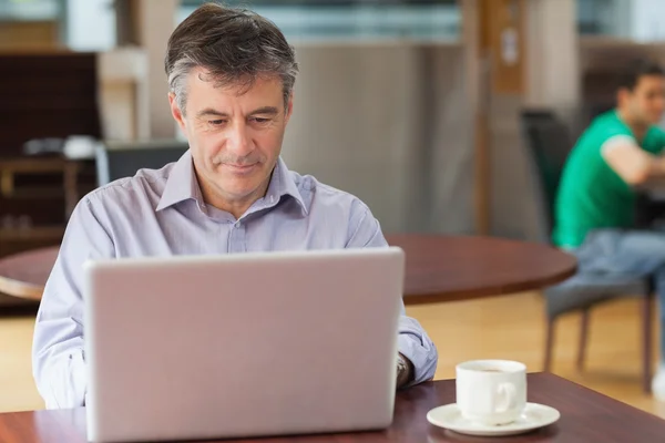 Homem em uma cafeteria trabalhando no laptop — Fotografia de Stock