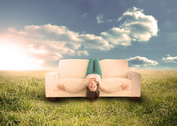 Woman sitting upside down on couch in field — Stock Photo, Image