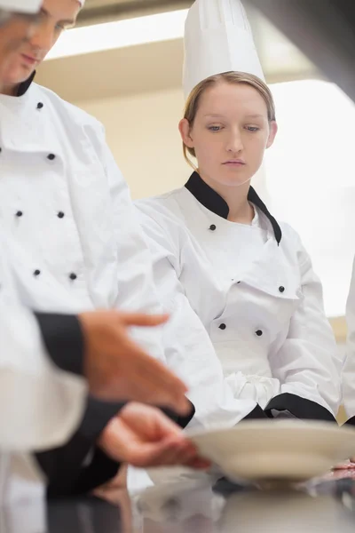 Femme réfléchie chef à la recherche d'une assiette — Photo