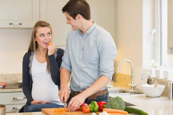 Мужчина режет овощи для беременной жены — стоковое фото