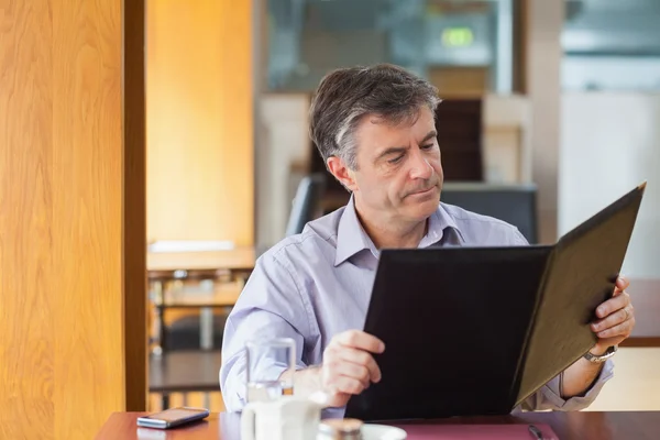 Man in a coffee shop looking at the menu — Stock Photo, Image
